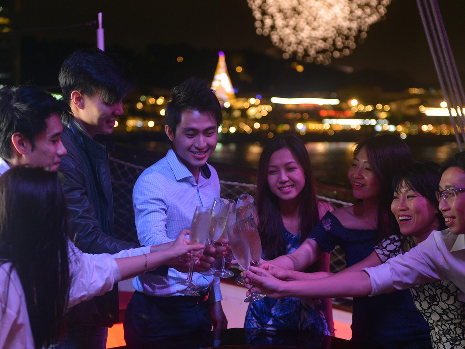 Guests raising champagne glasses on deck at midnight